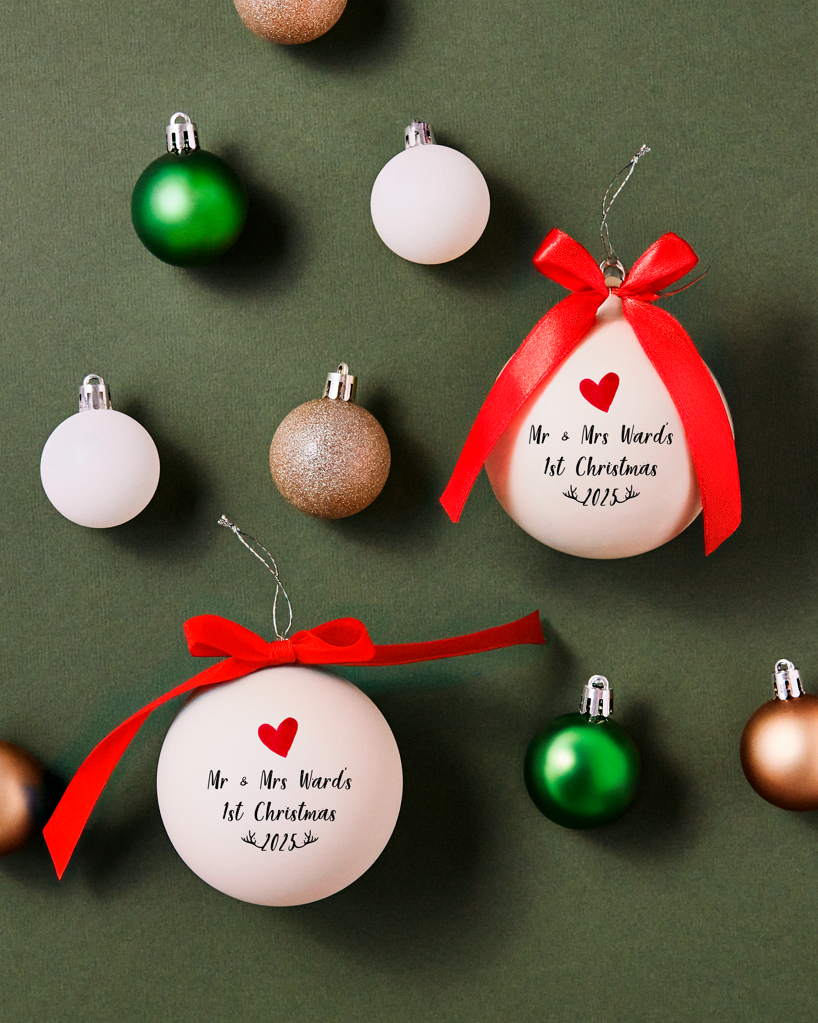 Pair of personalised Mr & Mrs 1st Christmas glass baubles with red bows surrounded by festive ornaments – elegant Christmas decorations for couples